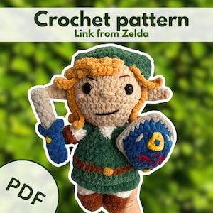 Könnte beinhalten: Eine Häkelanleitung als PDF für eine Link aus Zelda Plüschfigur. Die Figur trägt eine grüne Tunika und Mütze, hat spitze Ohren, blondes Haar, ein blaues Schwert und einen blauen Schild mit gelben und roten Details. Der Text lautet Crochet pattern Link from Zelda.