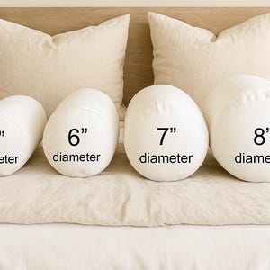May include: Four white bolster pillows with diameters of 5, 6, 7, and 8 inches are displayed on a bed. The pillows are cylindrical and oval-shaped. The text "diameter" is printed below each number.
