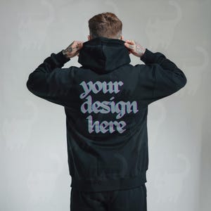 Könnte beinhalten: Schwarzer Kapuzenpullover mit dem Text "your design here" auf der Rückseite.