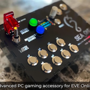 May include: A black gaming accessory with silver buttons and red, green, and blue lights. The text "SEA ONE" is printed on the accessory.  The accessory has labels for "Launch Drones", "Return Drones", and "Reconnect Drones".