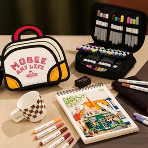 May include: A white and yellow cartoon-style carrying case with the text MOBEE ART LIFE, a black zippered organizer filled with colorful markers, a spiral-bound sketchbook with a building illustration, a checkered mug, and several loose markers.