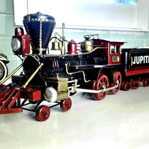 May include: A detailed model train with the word "JUPITER" on the side. The train features a black body with red and gold accents, including red wheels. The engine has a blue top and a red headlight. A decorative item.