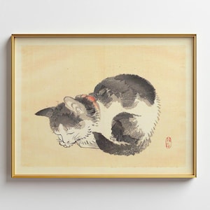 以下が含まれることがあります： 伝統的な日本のスタイルで描かれた、眠っている猫の額入りプリント。猫は黒と白のインクで描かれ、赤い首輪をしており、クリーム色の背景に配置されています。アートワークは金のフレームに収められています。