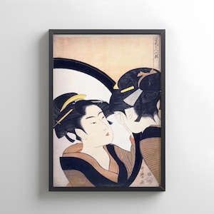 以下が含まれることがあります： 伝統的な衣装を着た女性2人を描いた、額入りの日本の木版画。このアートワークは、黒、金、くすんだアースカラーのパレットを使用しています。女性の髪は手の込んだアップスタイルにまとめられており、プリントはクリーム色の背景に配置されています。