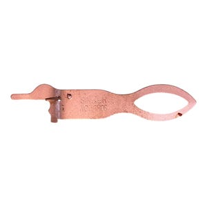 May include: A copper-colored metal sewing machine attachment with a pointed end, a central body featuring the embossed text SINGER NO 36806, and a rounded, open loop handle on the opposite side. The object has a flat, elongated, and symmetrical shape.