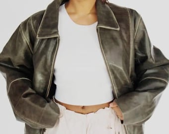 May include: A dark green leather jacket with a zipper closure and a collar. The jacket has a relaxed fit and is made of a soft, supple leather.