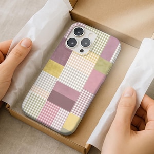 Puede incluir: Una funda de teléfono multicolor con un diseño de patchwork en una caja de cartón. La funda presenta cuadrados rosas, amarillos, verdes y grises. La funda del teléfono está rodeada de papel de seda blanco.