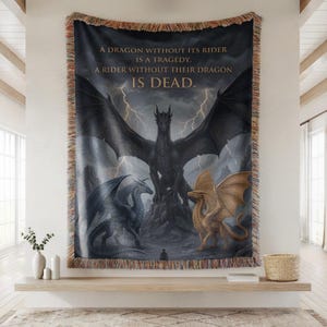May include: Woven tapestry featuring a dramatic dragon illustration with a dark color palette. The artwork depicts three dragons, a lone figure, and lightning. Text reads: "A DRAGON WITHOUT ITS RIDER IS A TRAGEDY. A RIDER WITHOUT THEIR DRAGON IS DEAD."