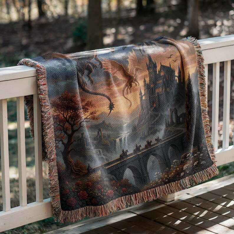 Pu&ograve; includere: Coperta tessuta con una scena fantasy con un castello, un ponte e draghi. L'opera d'arte &egrave; nelle tonalit&agrave; del grigio, marrone e arancione, con un bordo a frange. La coperta &egrave; drappeggiata su una ringhiera bianca.