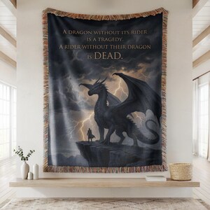May include: Woven tapestry featuring a dramatic dragon illustration with a rider on a cliff against a stormy sky. The text reads: "A DRAGON WITHOUT ITS RIDER IS A TRAGEDY. A RIDER WITHOUT THEIR DRAGON IS DEAD."