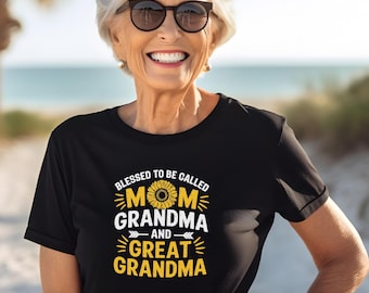 May include: Black t-shirt with the text "Blessed to be called Mom, Grandma, and Great Grandma." The text is in white and yellow, with a sunflower graphic. The person in the image is wearing sunglasses and smiling.