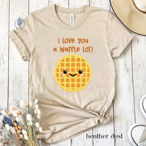 May include: A beige t-shirt with the text "I love you a waffle lot!" and a cartoon waffle with a smiling face.