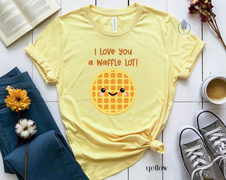 May include: Yellow t-shirt with the text "I love you a waffle lot!" and a cartoon waffle with a smiling face.