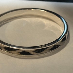 May include: A silver bangle bracelet with a braided band of black and white horsehair.