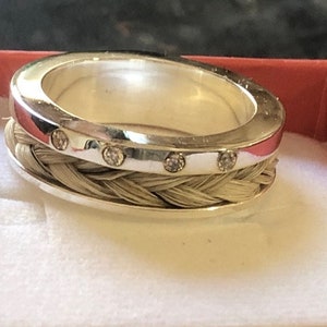 May include: A silver ring with a braided horsehair band and five small clear gemstones.