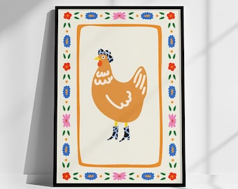 Op de afbeelding: Een ingelijste illustratie van een bruin kippetje met een blauwe en witte gebloemde hoed en laarzen. De lijst heeft een kleurrijke rand met bloemen en bladeren.