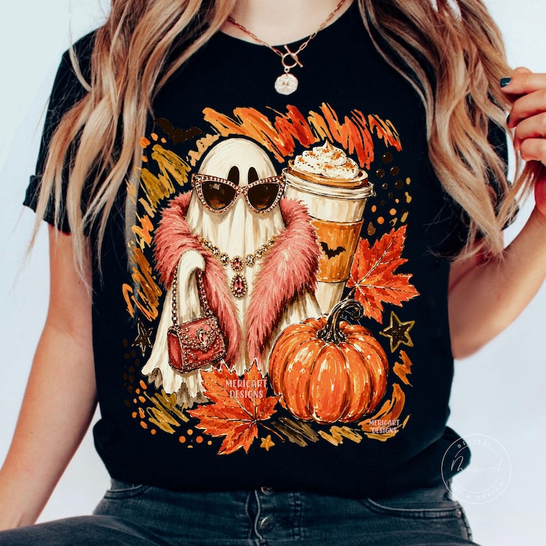 Puede incluir: Una camiseta negra con el gr&aacute;fico de un fantasma con gafas de sol de ojo de gato, una estola de piel sint&eacute;tica rosa y un collar dorado, sosteniendo un bolso rojo. Junto al fantasma hay una calabaza y un caf&eacute; rodeados de hojas de oto&ntilde;o.