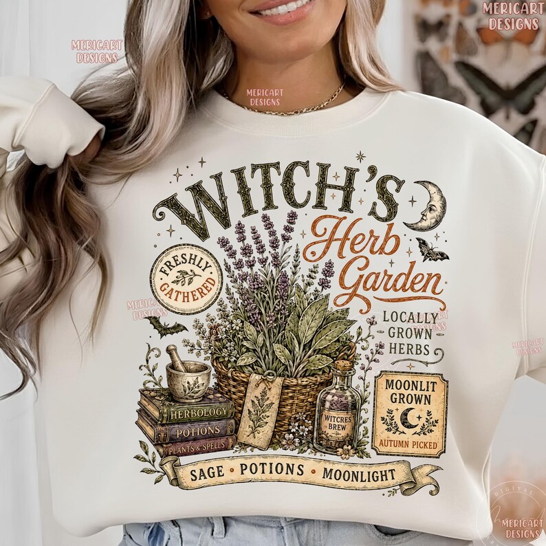 May include: A cream-colored sweatshirt featuring a graphic print with the text Witch's Herb Garden. The design includes a basket of herbs, a mortar and pestle, stacked books labeled Herbology, Potions, and Plants & Spells, and a potion bottle.