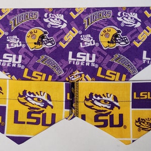 May include: Three purple and gold dog bandanas with the LSU Tigers logo. The bandanas are in different sizes and have different patterns. The largest bandana has a repeating pattern of the LSU Tigers logo, the LSU Tigers wordmark, and the words "LSU Tigers". The two smaller bandanas have a repeating pattern of the LSU Tigers logo and the LSU Tigers wordmark.