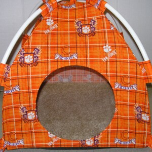 May include: Orange and white pet tent with a paw print and "Paw Power" text. The tent has a round opening and a brown fleece lining.