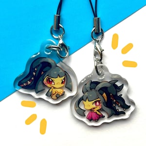 Puede incluir: Dos encantos de acrílico transparente con un personaje de dibujos animados con cabello negro y ojos amarillos. El personaje lleva una falda rosa y tiene una boca grande con dientes afilados. Los encantos están unidos a cordones negros con cierres plateados.
