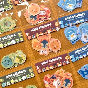 Può includere: Una collezione di mini adesivi colorati in confezioni di plastica trasparente. Gli adesivi presentano vari personaggi dei cartoni animati, inclusi disegni di partenza di fuoco, acqua ed erba. Ogni confezione è etichettata con "mini stickers".