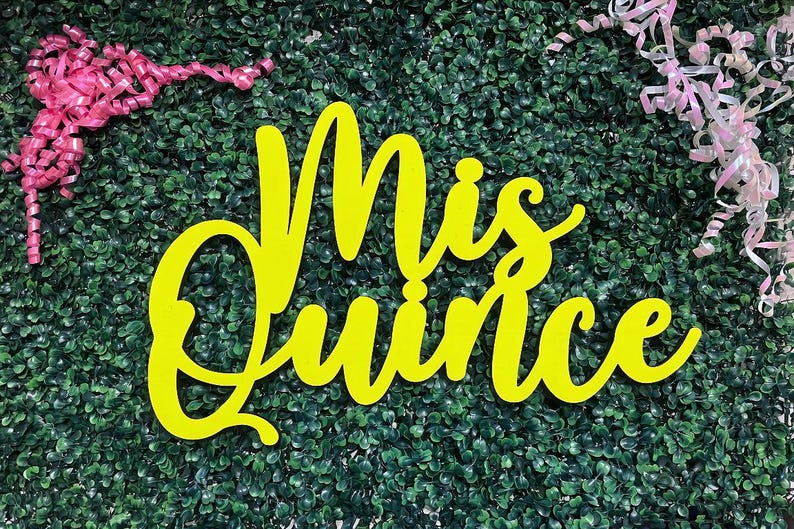Op de afbeelding: Een felgeel bord met de tekst Mis Quince in een cursief lettertype. Het bord is geplaatst tegen een donkergroene bladerrijke achtergrond met roze krullende linten in de linker- en rechterbovenhoek van de weergave.