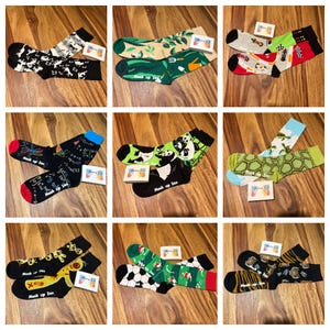 May include: Nine pairs of colourful socks with various designs, including a panda, a turtle, a tiger, a football, and a garden scene. The socks are all made by the brand "Mash Up Sox".