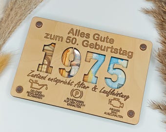 May include: A wooden plaque with the number "1975" cut out, filled with currency. The plaque has the text "Alles Gute zum 50. Geburtstag" and other German text. Decorative elements include small screws in each corner.