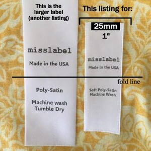 May include: Two white rectangular fabric labels with black text. The left label is 33mm wide. The right label is 25mm or 1 inch wide, labeled 'misslabel', 'Made in the USA', 'Soft Poly-Satin', and 'Machine Wash', with a horizontal fold line.