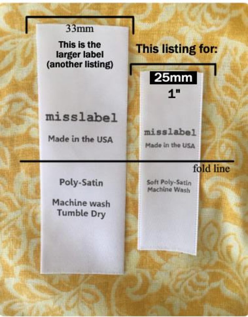 May include: Two white rectangular fabric labels with black text. The left label is 33mm wide. The right label is 25mm or 1 inch wide, labeled 'misslabel', 'Made in the USA', 'Soft Poly-Satin', and 'Machine Wash', with a horizontal fold line.