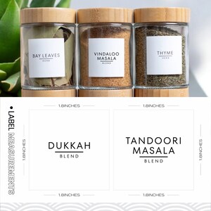 May include: Six glass spice jars with bamboo lids and labels. The labels are white with black text and include the names of the spices: Bay Leaves, Vindaloo Masala, Thyme, Dukkah, Tandoori Masala. Each jar is 1.8 inches wide and 1.8 inches tall.