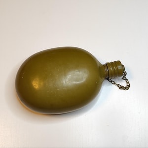 May include: A green metal canteen with a metal chain attached to the lid.