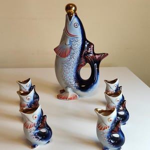 Puede incluir: Un juego de siete vasos de chupito de porcelana azul y blanca con forma de pez. El juego incluye una decantador más grande con forma de pez con una tapa dorada.