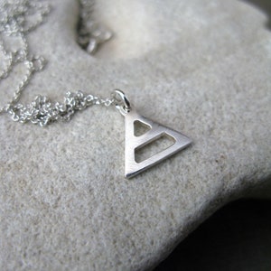 May include: A silver necklace with a geometric triangle pendant. The pendant has a hollow design with a smaller triangle inside.