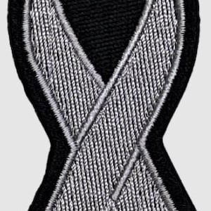 Puede incluir: Parche bordado de cinta de concienciación negra y plateada. La cinta es plateada con un aspecto texturizado, delineada con hilo plateado, sobre un fondo negro. El parche está diseñado para ser cosido a la tela.