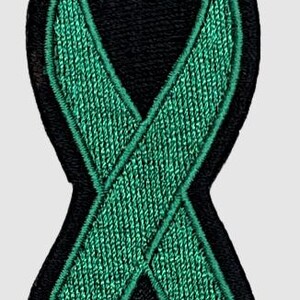 May include: Green ribbon embroidered patch with black outline. The ribbon is tied in a knot and is a symbol of awareness and support.