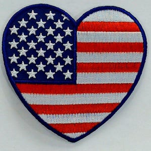 May include: A red, white and blue American flag in the shape of a heart. The flag is embroidered with white stars on a blue field and red and white stripes.