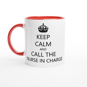 Puede incluir: Taza de cerámica blanca con borde rojo. La taza tiene una corona negra y el texto "Keep Calm and Call the Nurse in Charge".