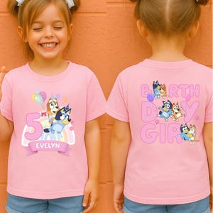 A young girl wearing a pink t-shirt with a cartoon character and the text "5 EVELYN" printed on it.