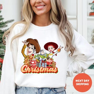 A woman wearing a white sweater with a Christmas-themed graphic design featuring characters from the Toy Story franchise.