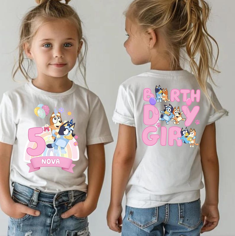 A young girl wearing a white t-shirt with a cartoon character and text printed on it.