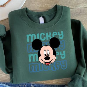 A green sweatshirt with a Mickey Mouse graphic printed on it.