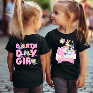 Two young girls wearing black t-shirts with birthday-themed designs.