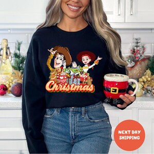 A woman wearing a black sweater with a Christmas-themed graphic and holding a red mug with a Santa Claus design.