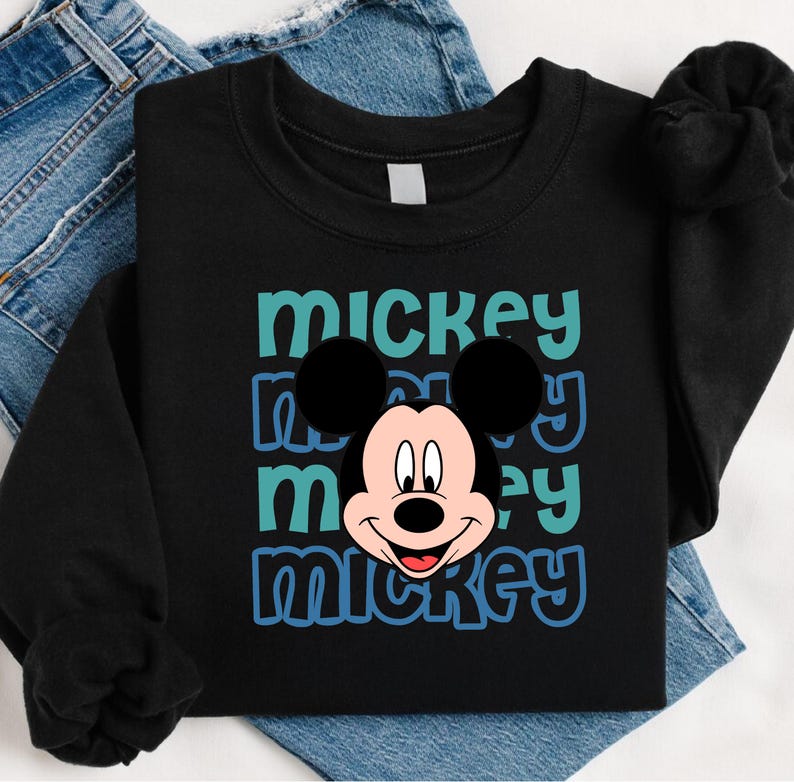 A black t-shirt with a Mickey Mouse graphic printed on it, along with a pair of blue jeans.
