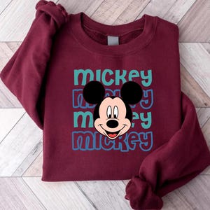 A burgundy sweatshirt with a Mickey Mouse graphic printed on it.
