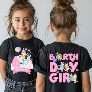 A young girl wearing a black t-shirt with a birthday theme, featuring cartoon characters and the text "6 SCARLET" on the back.