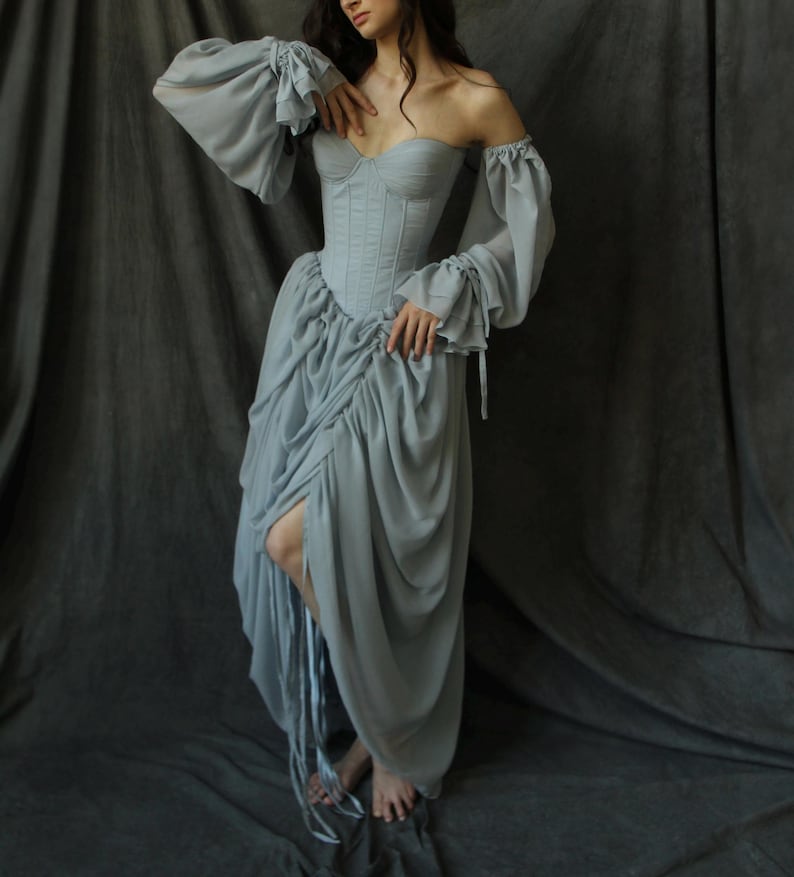 May include: A light blue off-the-shoulder dress with a fitted bodice and a flowing skirt. The dress has a corset-style top with boning and a gathered skirt.