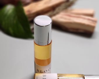 May include: Two small glass bottles with silver caps and labels that say "BLOOM Parfum 10 ml | .34 oz". The bottles are filled with a light yellow liquid.